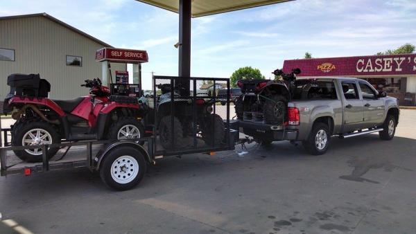 Photo of ATVs loaded on a truck and trailer.